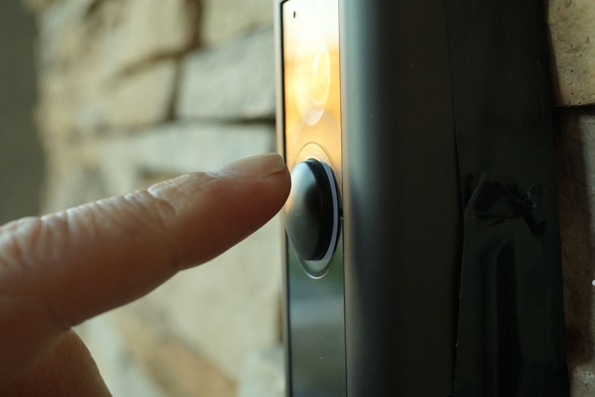 A person pressing the button on a smart doorbell, enhancing home security with video capabilities.
