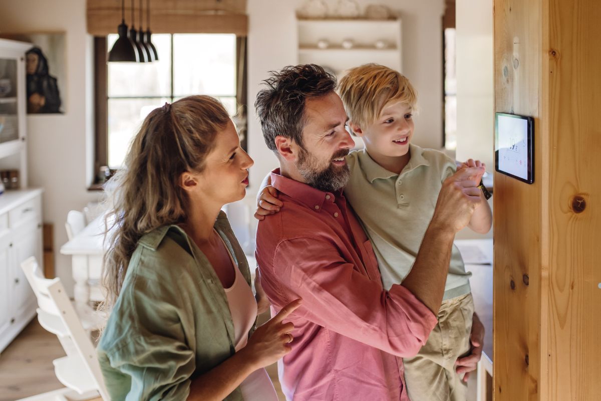 A family observes a digital clock in their kitchen, highlighting their smart home technology and home security service.