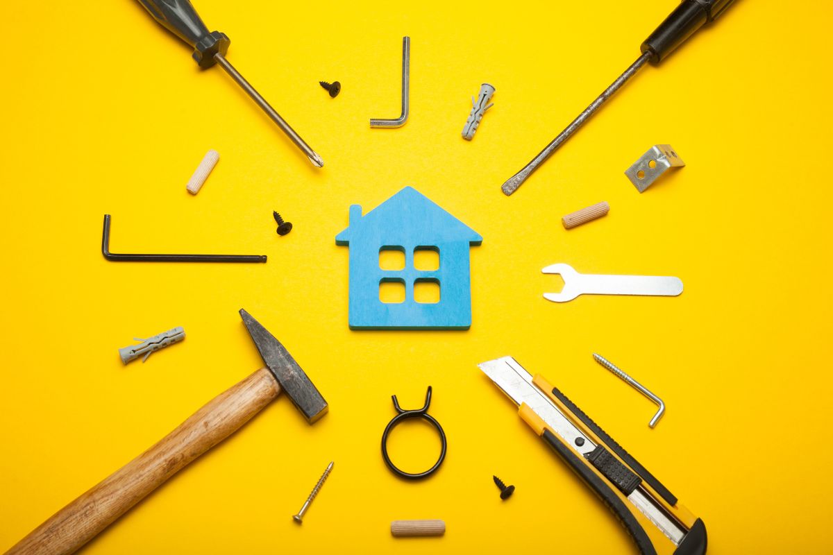 Various tools, such as a screwdriver and pliers, displayed alongside a house outline against a vibrant yellow backdrop.