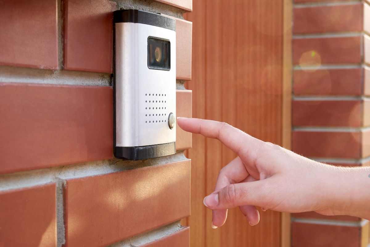 A person pressing a button on a doorbell, ready to announce their arrival at the entrance of a home.