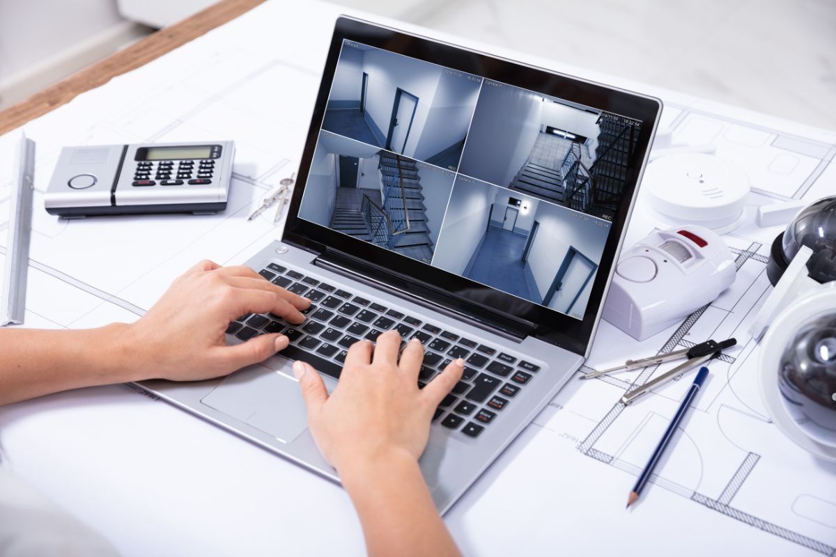 A person typing on a laptop with a built-in camera, focused on their work in a well-lit environment.