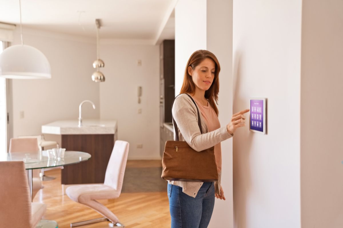 A woman stands in front of a wall-mounted touchscreen, engaging with the display in a modern environment.